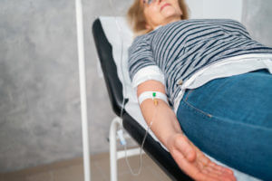 senior female patient lying on the examination table while receiving IV infusion therapy