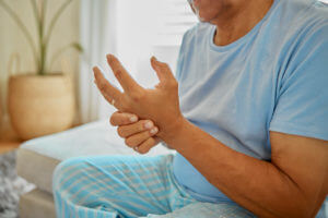An older man holding his hand an experiencing Rheumatoid Arthritis pain