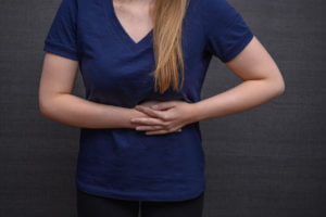 A woman is suffering abdominal pain on the left side of her stomach, which could be a sign of Crohn's disease.