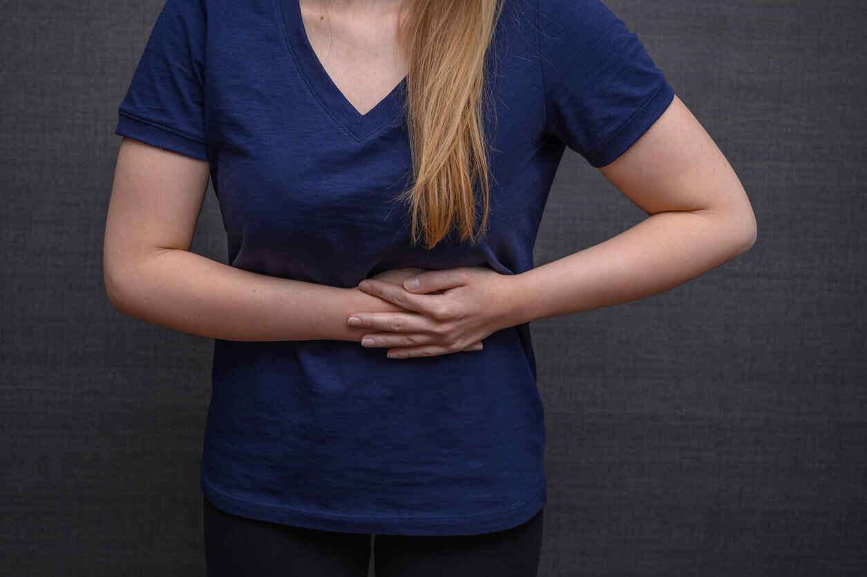 A woman is suffering abdominal pain on the left side of her stomach, which could be a sign of Crohn's disease.