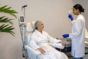 A female doctor doing IV infusion for senior woman patient in beauty clinic.