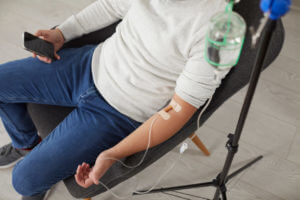 Patient receiving Remicade infusion therapy through IV drip while seated, treatment for autoimmune conditions such as Crohn’s disease, ulcerative colitis, and rheumatoid arthritis