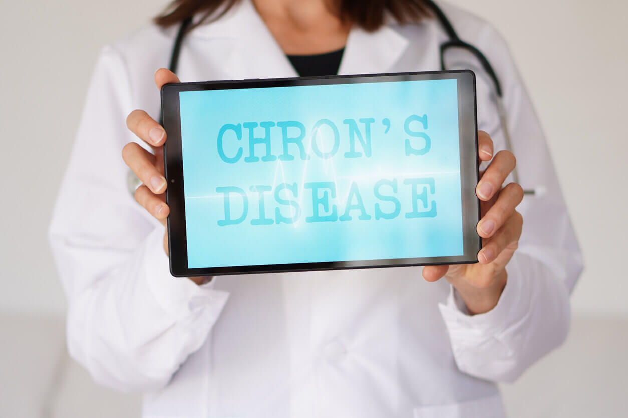 A female doctor is holding a tablet that displays the word Crohn's disease.