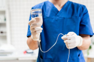 Doctor in blue uniform holding drip iv and infusion pump.
